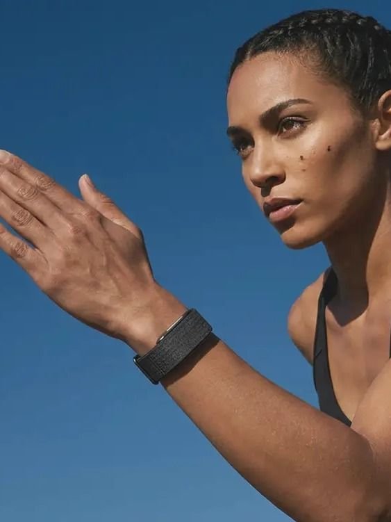 Athletic woman wearing Hume Band outdoors against blue sky — metabolic momentum building